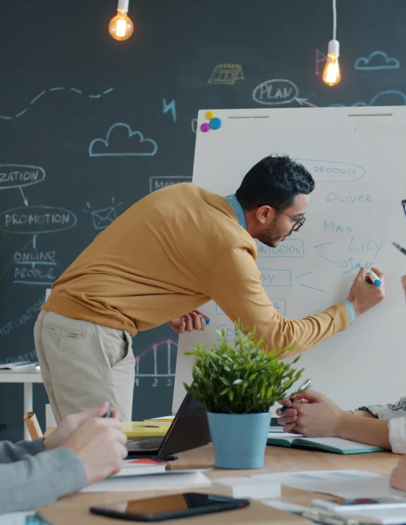 Consultant presenting ideas on a whiteboard to colleagues