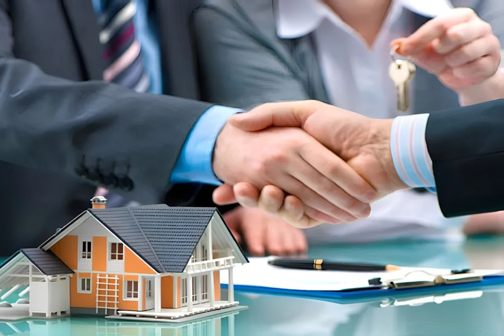 Two people shaking hands over a house model