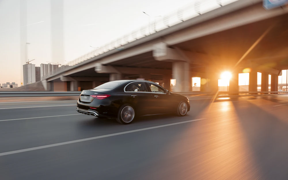 Black executive car driving at sunset